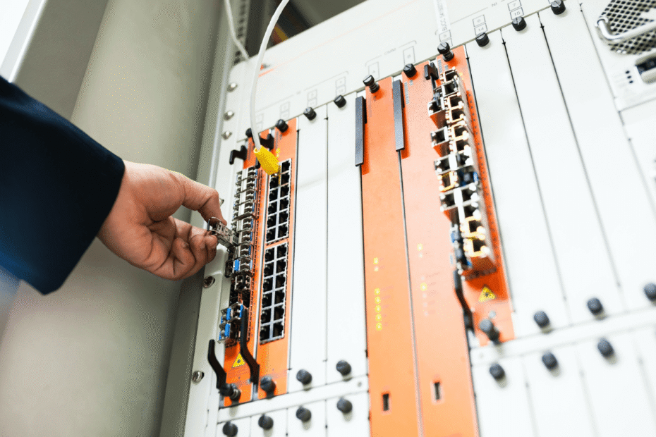 Mão de técnico conectando cabo de rede diretamente em um rack, ilustrando o que é um servidor dedicado e a exclusividade do hardware físico.